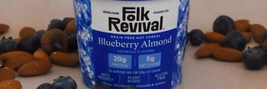 A Folk Revival Blueberry Almond hot cereal cup surrounded by fresh blueberries and almonds.