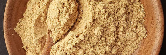 Acorn flour in a wooden bowl with a wooden spoon.